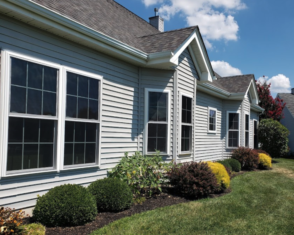 Exterior view of light gray home with white double hung windows with grids