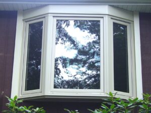 Exterior view of white ,three lite bay window with fixed center Picture windows and two operational Casement windows.