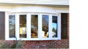 Exterior view of a white, five lite casement bow window in a brick house.