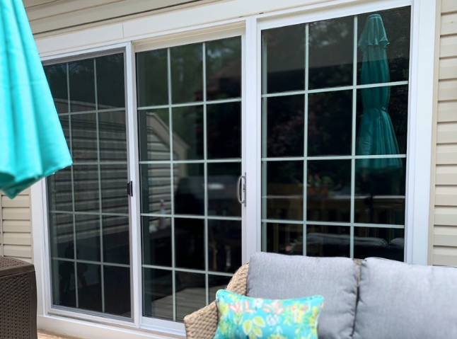 three panel sliding glass patio door on outdoor deck with grids, in white.
