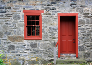 Old, stone building with a red door and window. Demonstrates how contrasting colors add interest.