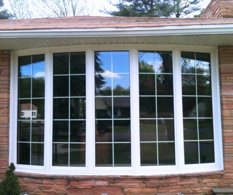 Exterior view of a five lite, bow window with colonial grids on a stone house.