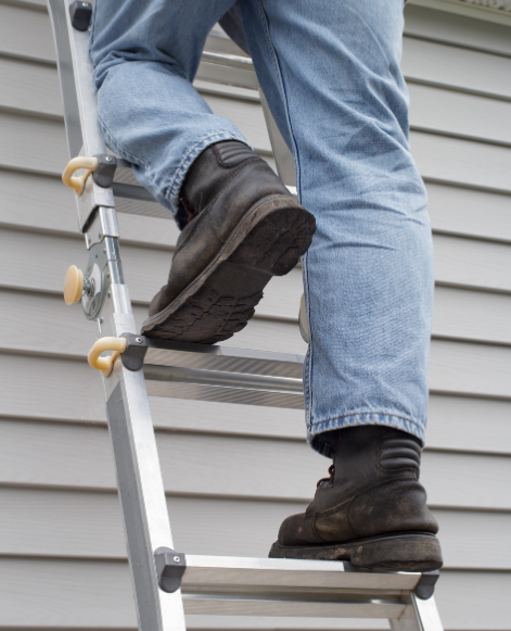Close up of man climbing ladder with work boots
